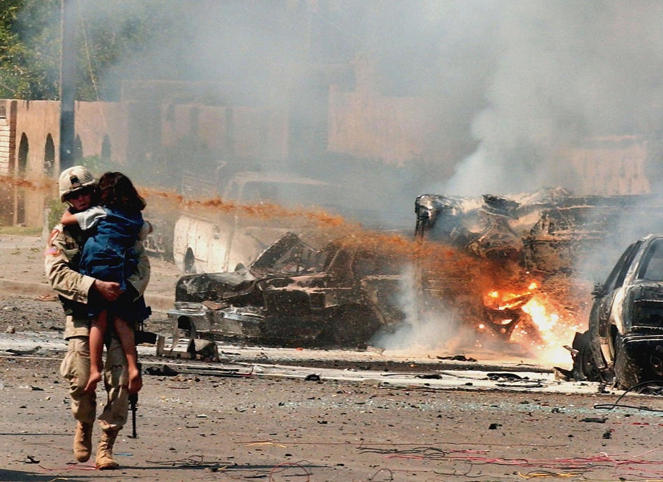Американский солдат несет иракскую девочку подальше от места трех взрывов 30 сентября 2004 в Багдаде.