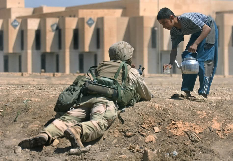 Иракский мальчик предлагает немного воды морскому пехотинцу. Багдад, 11 апреля 2003.