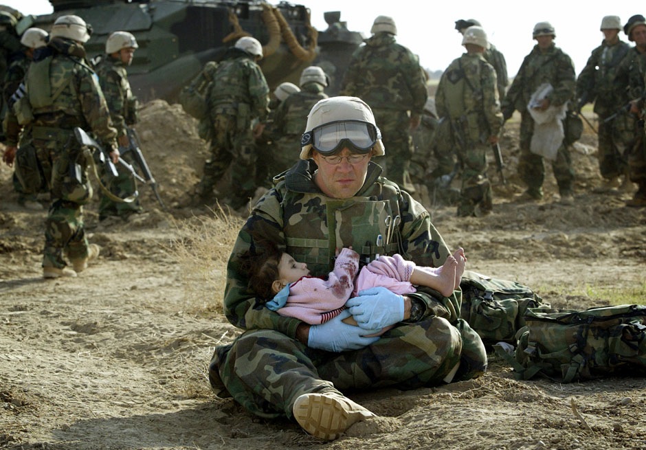 Полевой медик первого класса Ричард Барнетт из 1-й дивизии морской пехоты США держит на руках иракского ребенка, 29 марта 2003 года.